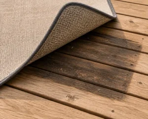 Outdoor carpet wooden deck discoloration visible after lifting the carpet.