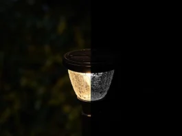Outdoor solar lights flash shown mid-flicker on a garden post fixture at night.