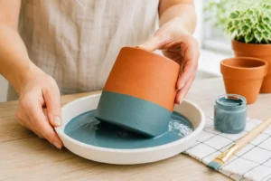 Dipping a pot using one of several painted terracotta pot ideas covered in this guide.